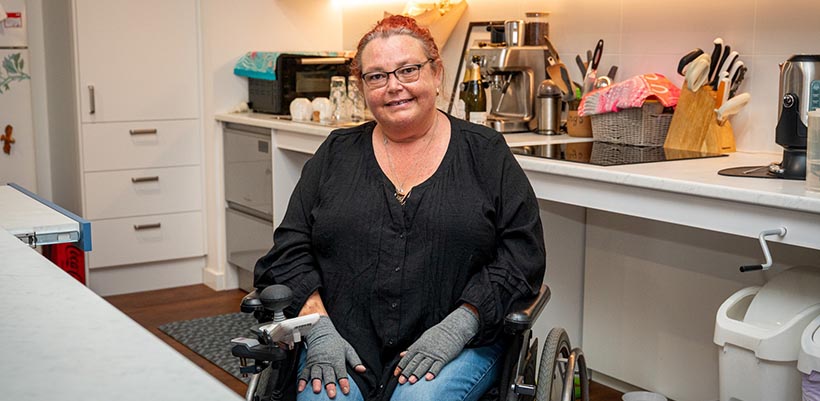 Jen sitting in a wheelchair in the kitchen area of her new purpose built home.