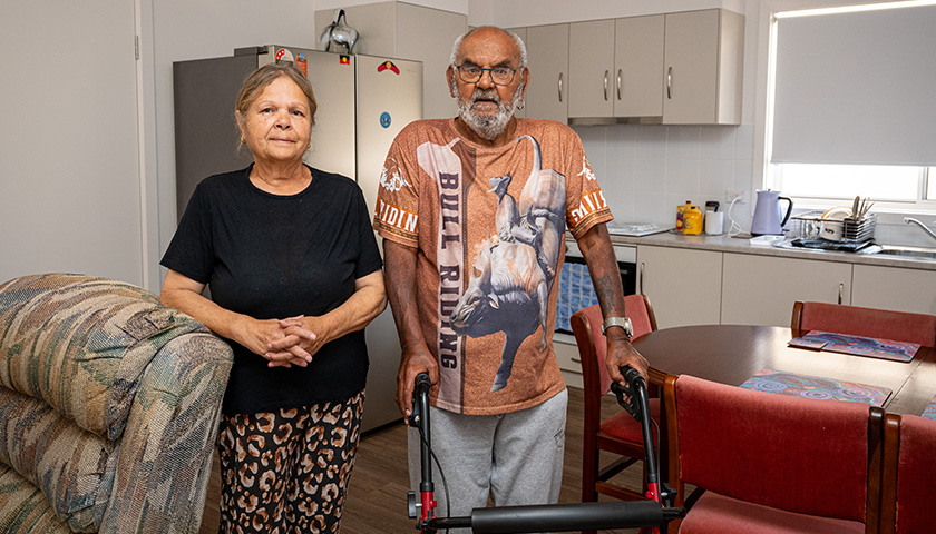 An Aboriginal woman and man standing in a kitchen looking directly at the camera.