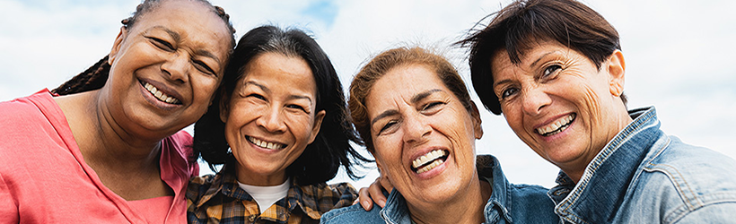 Head shot of four women huddled together smiling.