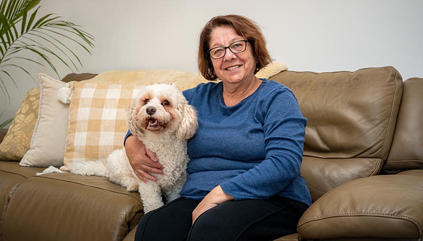 Rosaria at home sitting on the couch with her dog "Sonny"
