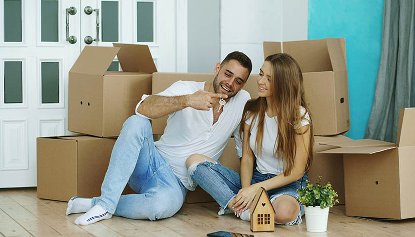 Couple sitting on the lounge room floor holding a set of keys