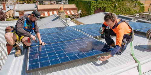 Tradespeople installing solar panels on a roof